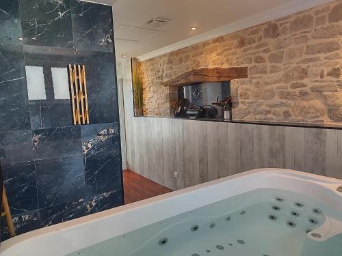 a bath tub in a bathroom with a stone wall at Belle Quercynoise hammam et jaccuzi privatifs in Septfonds