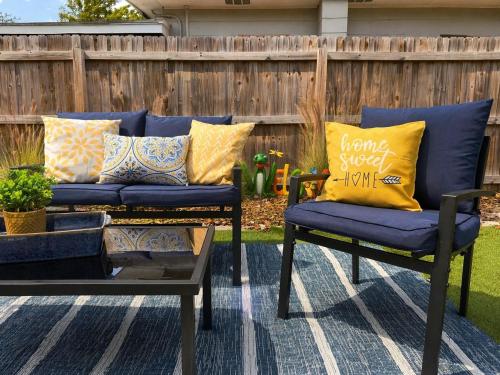 a patio with two blue chairs with yellow pillows at NEW Beach Cozy Bungalow 2B Mins-beach&downtown in Clearwater