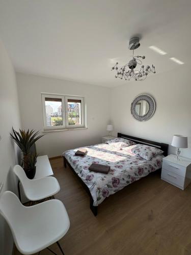 a bedroom with a bed and two white chairs at Biebrzańska Dolina 2 in Goniadz