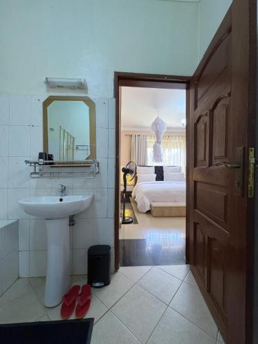 a bathroom with a sink and a mirror and a bed at The Terrace Villa in Kampala
