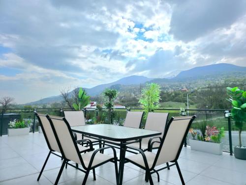 a table and chairs on a balcony with mountains at Villa Panorama View Brezovica in Brezovica