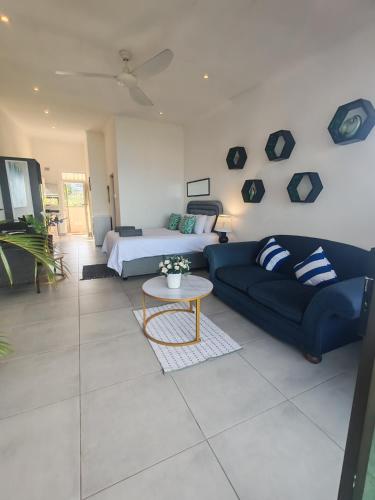 a living room with a blue couch and a table at Aloe Shore- Whale Watch from Balcony- Stunning in Umdloti