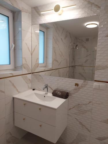 a white bathroom with a sink and a mirror at Domki Alpati in Jastrzębia Góra