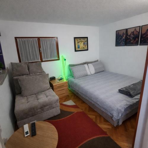 a bedroom with a bed and a couch and a chair at Šumarak Weekend House in Arandelovac