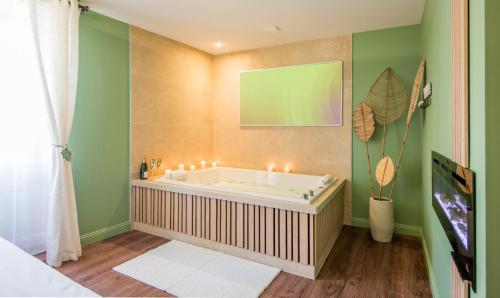 a bathroom with a tub with candles and a green wall at Ecrin de bulles - Jacuzzi & clim in Les Cabannes