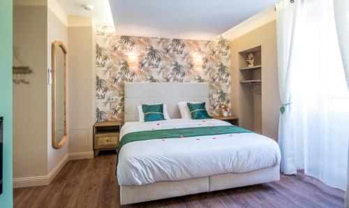 a bedroom with a large white bed with blue pillows at Ecrin de bulles - Jacuzzi & clim in Les Cabannes