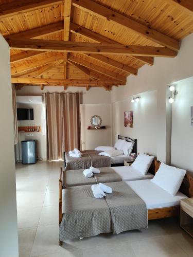 a bedroom with three beds and a wooden ceiling at ChristAlex Guesthouse in Himare