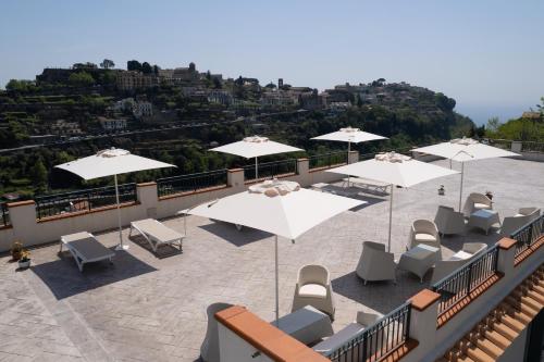 a group of white umbrellas and chairs on a balcony at Guesthouse with Suites on the Amalfi Coast - Residence Villa Ruocco near Amalfi - 300sqm Open Terrace near Ravello - Breathtaking View in Scala