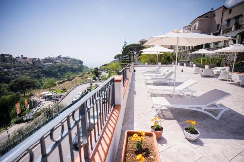 a balcony with tables chairs and umbrellas and a road at Guesthouse with Suites on the Amalfi Coast - Residence Villa Ruocco near Amalfi - 300sqm Open Terrace near Ravello - Breathtaking View in Scala