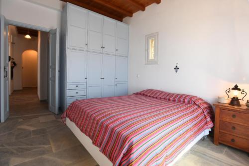 a bedroom with a large bed and a wooden dresser at Tinos Sky View Villa in Arnados