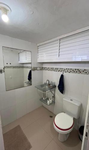 a white bathroom with a toilet and a mirror at 30 metros do mar, 2 quartos! in Pontal do Paraná