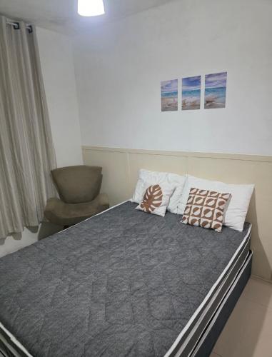 a bedroom with a bed with pillows and a chair at 30 metros do mar, 2 quartos! in Pontal do Paraná