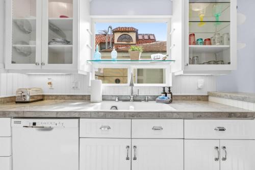 a kitchen with white cabinets and a sink at Stunning beach home - steps2sand, AC, Large Patio and Fast Wifi! in San Diego
