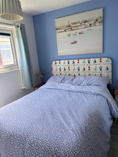 a bedroom with a bed with a blue wall at Sally Chalet in Hemsby