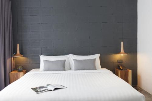 a bedroom with a large white bed with a book on it at La Pause Hatyai in Hat Yai
