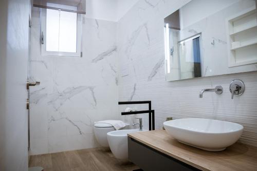 a white bathroom with two sinks and a toilet at dellarocca4 in Cefalù