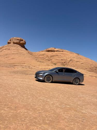 a silver car parked in the desert at وادي رم مخيم عادل in Wadi Rum