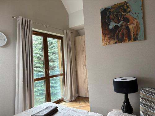 a bedroom with a window and a painting on the wall at Górski Błękit in Szklarska Poręba