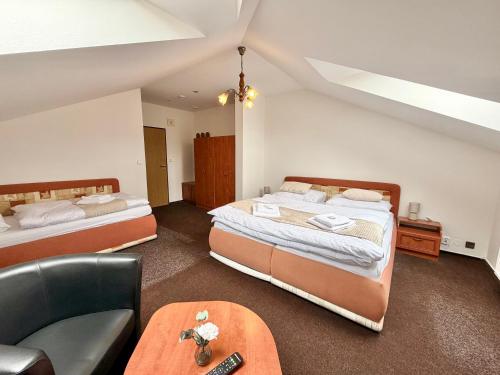 a room with two beds and a chair and a couch at Hotel Zlatý Kříž in Teplice