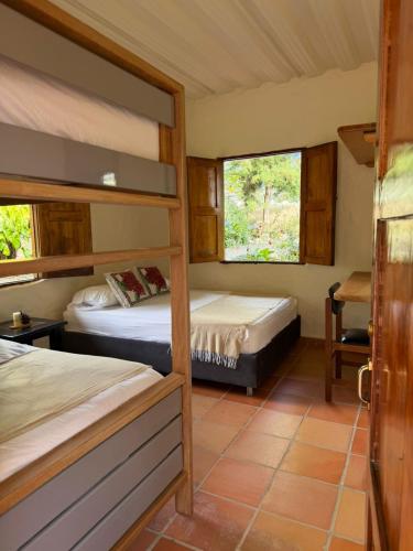 a bedroom with two bunk beds and two windows at Finca Hostal Ágora in Jardin