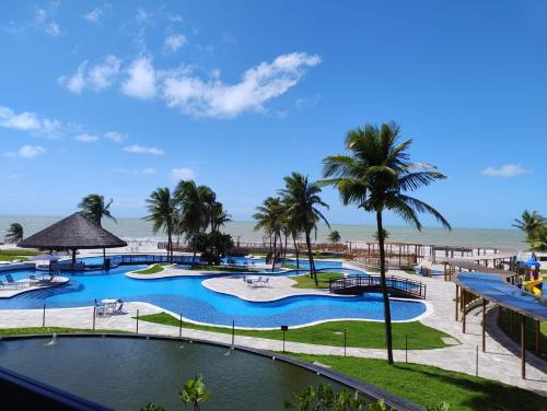 a view of a resort pool with palm trees and the ocean at Hotel Pirâmides natal in Natal