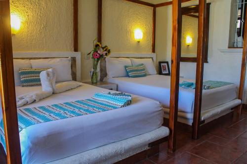 two twin beds in a room with two mirrors at Chez Waffle Hotel in Puerto Aventuras