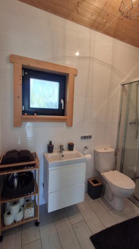 a bathroom with a sink and a toilet and a window at Slow Lake House Koszarka in Gródek Nad Dunajcem