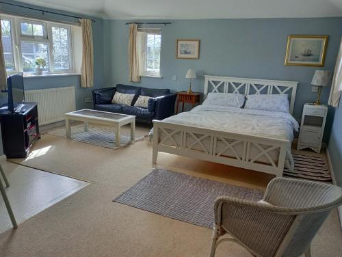 a bedroom with a bed and a living room with a couch at Wisteria House in Blean