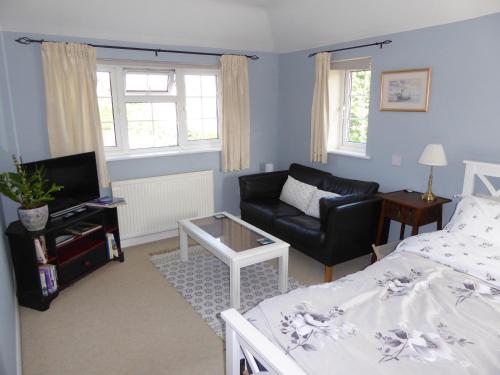 a living room with a bed and a couch at Wisteria House in Blean