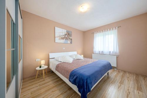 a bedroom with a bed with a blue blanket and a window at Villa Fila in Sinj