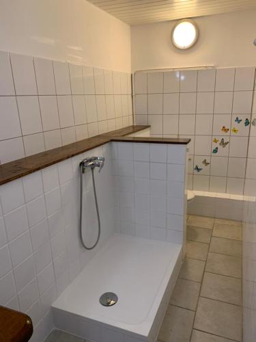 a white tiled bathroom with a shower and a tub at Les Manguiers in Deshaies