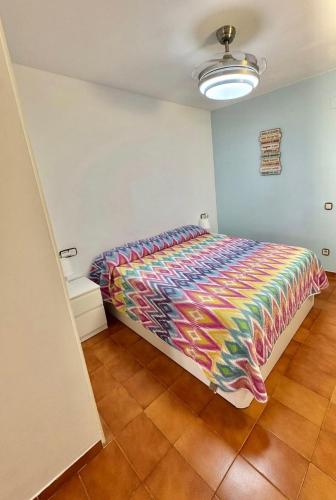 a bedroom with a bed with a colorful comforter at Apartamento Tossa in Tossa de Mar