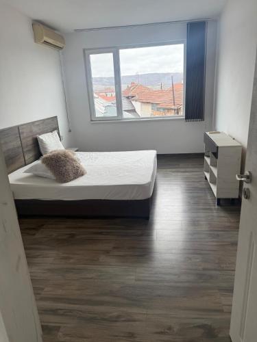 a bedroom with a bed and a large window at Уютът на Ясен in Yasen