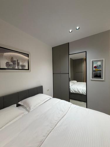 a bedroom with a white bed and a mirror at Sako Apartaments 2 in Golem