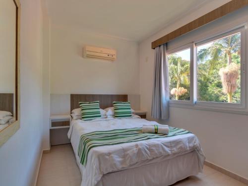 a bedroom with a bed and a large window at Villa Maciel Bombinhas in Bombinhas