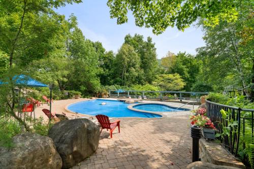 a pool in a yard with chairs and trees at Tremblant Prestige - Manoir 108-2 in Mont-Tremblant