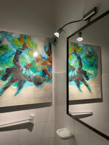 a bathroom with a painting on the wall and a mirror at The happy smile villa in Bella Farnia