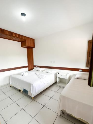 zwei Betten in einem Zimmer mit weißen Wänden in der Unterkunft Morro da Saudade in Cayru