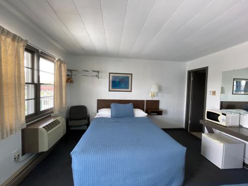 a bedroom with a large bed with a blue blanket at Colonial motel in Wisconsin Dells