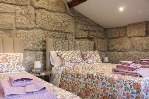 a bedroom with two beds and a stone wall at Quinta das Flores da Mãe in Folhada