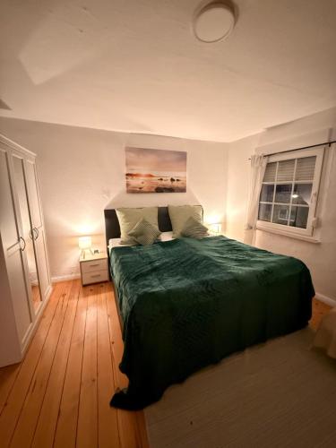 a bedroom with a green bed and two windows at Gästezimmer in Hafennähe in Waren