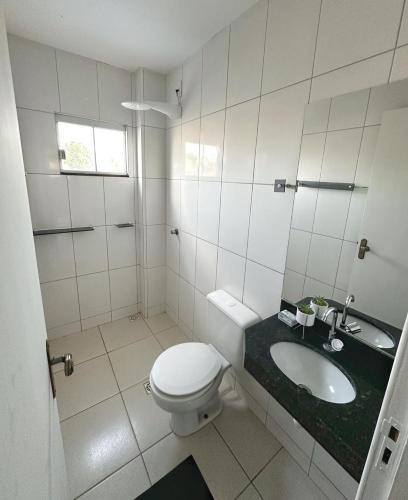 a white bathroom with a toilet and a sink at Hotel Santorini in Trindade
