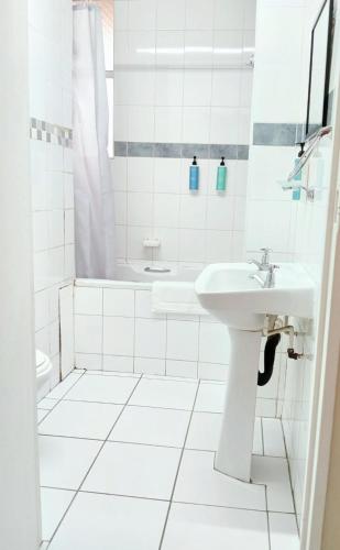 a white bathroom with a sink and a tub at Durban Oceanic Apartment 117 in Durban