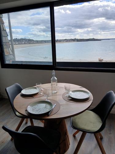 a wooden table with chairs and a table and a window at Studio très belle vue mer in Pléneuf-Val-André