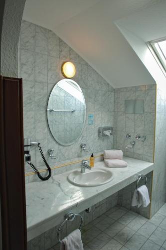 a bathroom with a sink and a mirror at Gräfliches Hotel Alte Post in Bad Birnbach