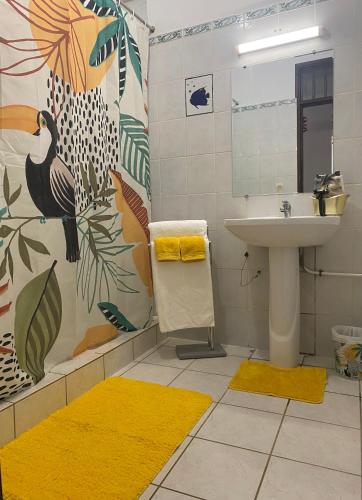 a bathroom with a sink and a shower with yellow rugs at Spacieux et lumineux Appartement T3 Cayenne in Cayenne