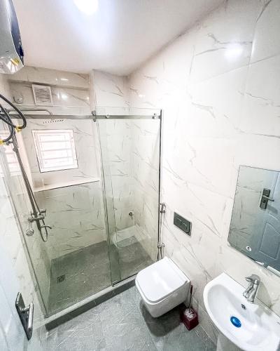 a bathroom with a shower and a toilet and a sink at Abuja Lux Apartment Wuye in Abuja