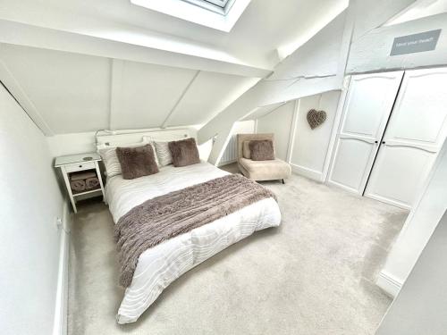 a white bedroom with a bed and a chair at Cosy Coastal Cottage in Tynemouth
