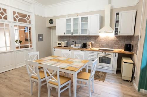 a kitchen with white cabinets and a table and chairs at Kispolgár Vendégház in Sárospatak
