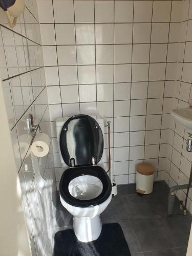 a bathroom with a toilet with a black seat at Woonwagen Carpe Diem in Oudwoude